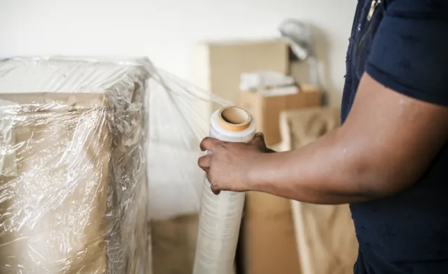 Movers wrapping a box